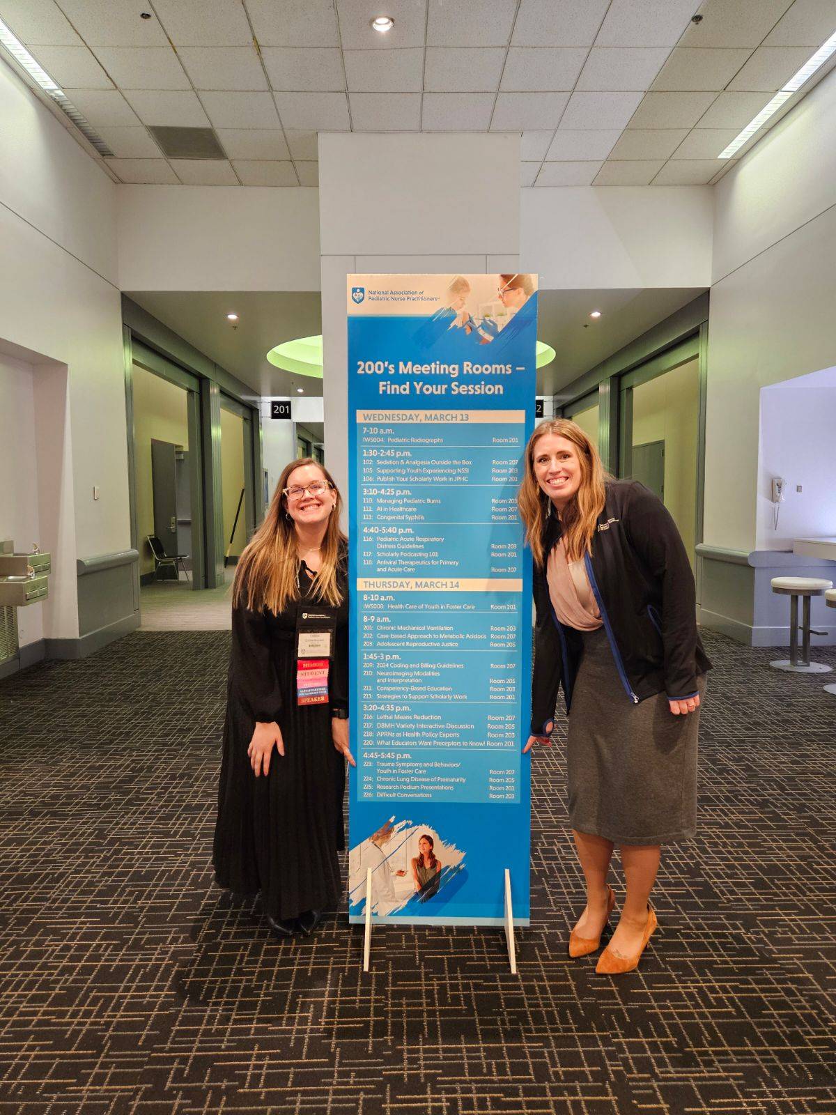 Quick and Buchele standing by banner with presentation listed